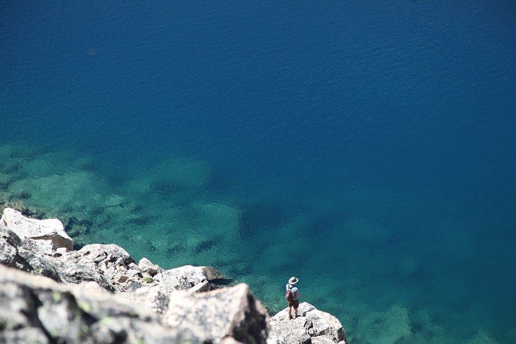 A spinning rod resting against a boat on a calm lake